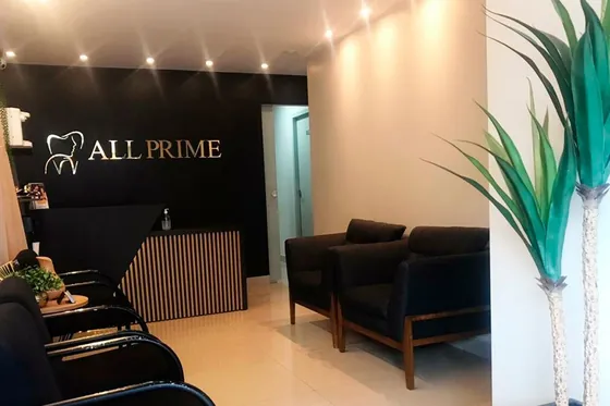 A recepção da All Prime: o balcão de madeira, as poltronas escuras e a logo dourada na parede preta.